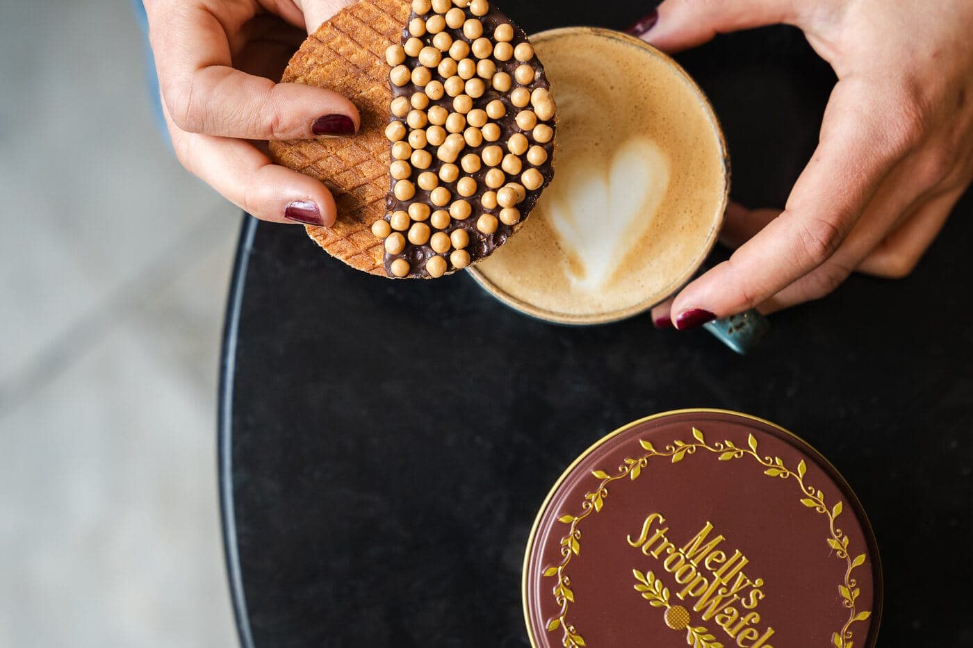 A stroopwafel resting on a cappuccino to warm it, the classic cup trick