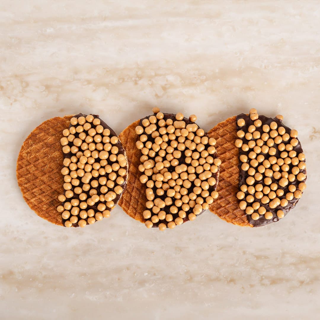 Drie verse stroopwafels gedoopt in chocolade en afgewerkt met karamelparels